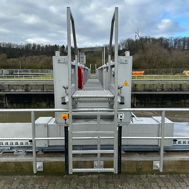 Leiter und Gitterrostbrücke über Trübwasser